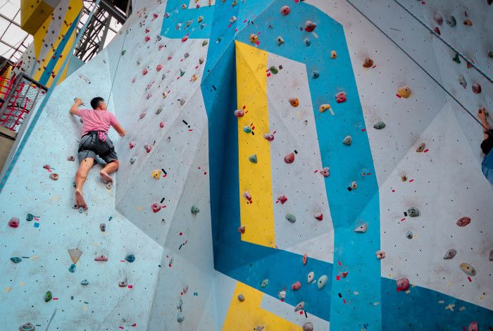 a young man doing indoor rock climbing