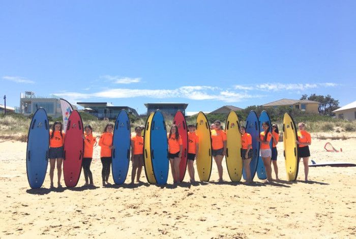 Young people standing on the beach in a life holding life saving surf boards