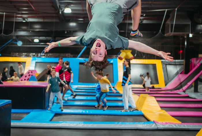 Young person at trampoline park jumping on a trampoline doing a backflip in the air