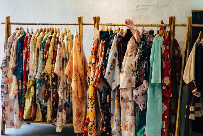 colourful t-shirts hanging on wooden clothes rack