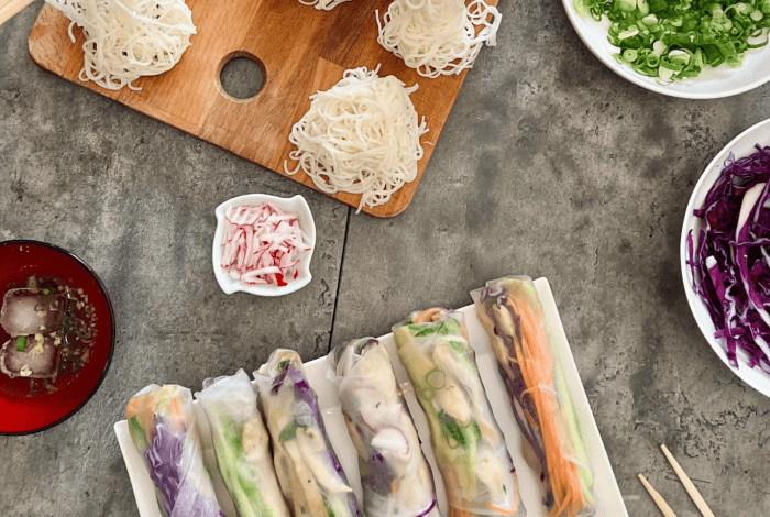 An image of Rice Paper Rolls with various fresh ingredients in bowls like noodles, purple cabbage and Spring onion