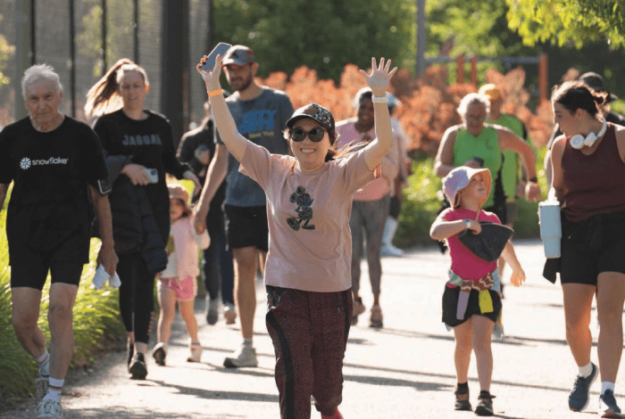 Woman running with her hands in the air, with more people following behind her