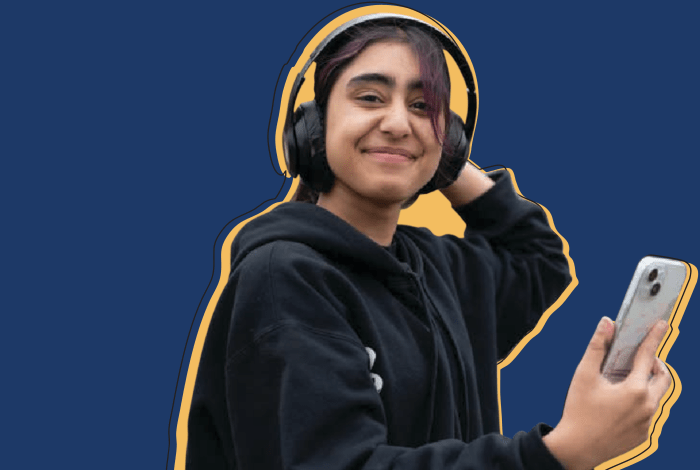 A young person holding a phone smiling