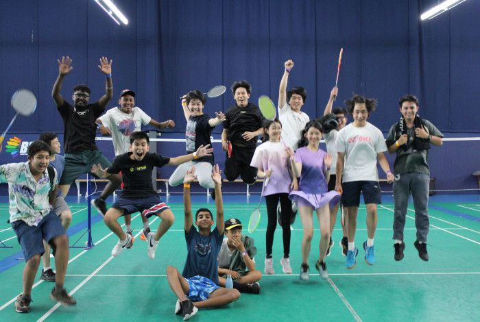 A group of Badminton players jumping, holding rackets