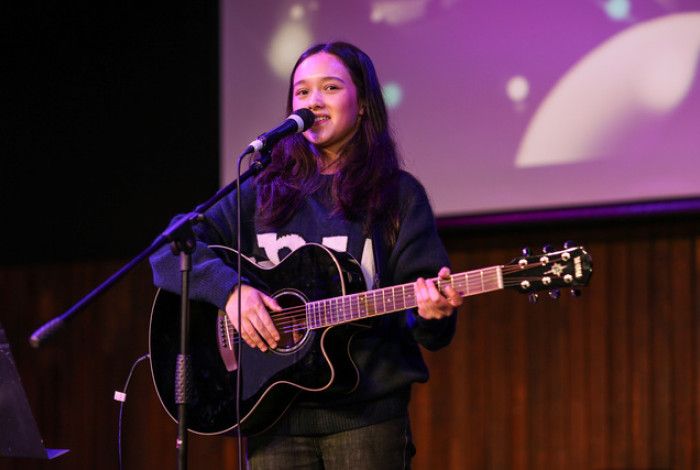 Young person playing guitar and singing