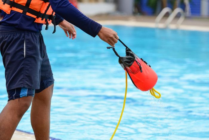 Lifeguard throwing rescuse equipment in water