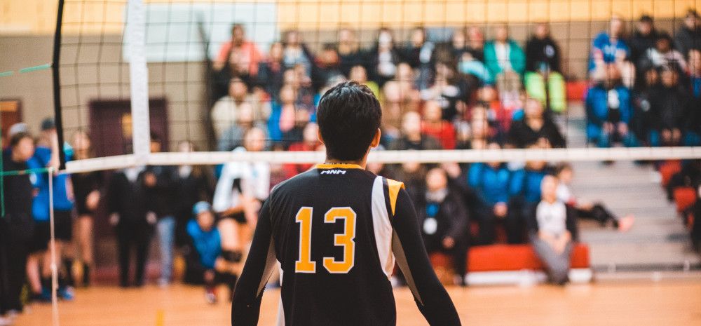 Young male stood in front of a volleyball net