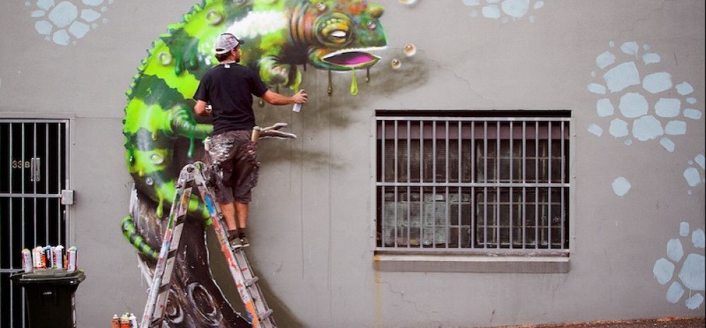 Aman painting a wall mural with camelion
