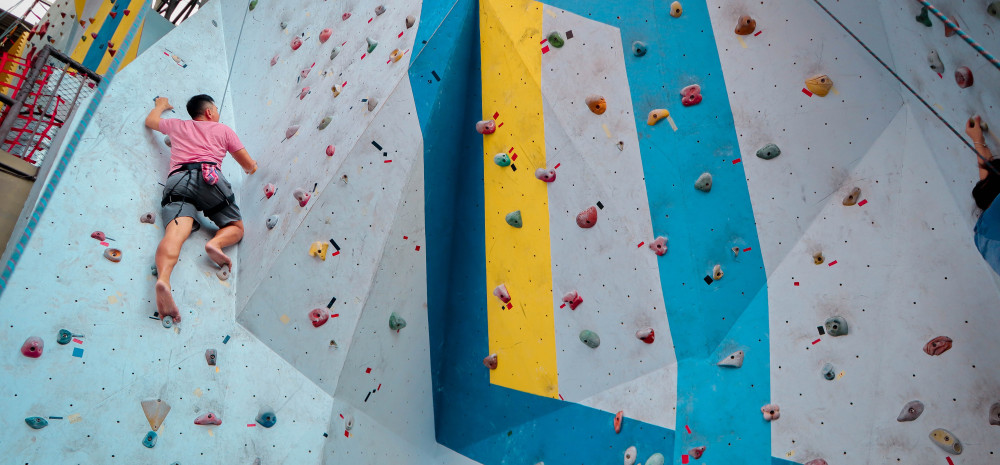 a young man doing indoor rock climbing