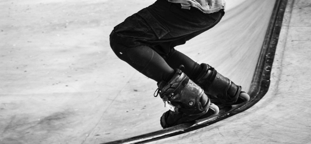 Person wearing rollerblades dropping into a skate bowl