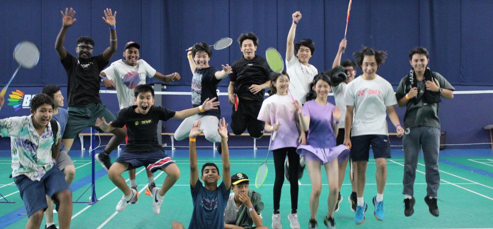 A group of Badminton players jumping, holding rackets