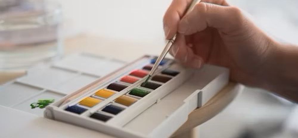 Person dipping brush into paint