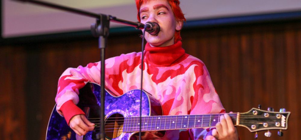 Young person playing guitar and singing