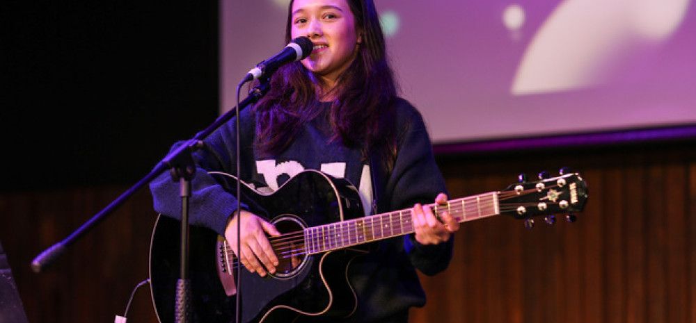 Young person playing guitar and singing