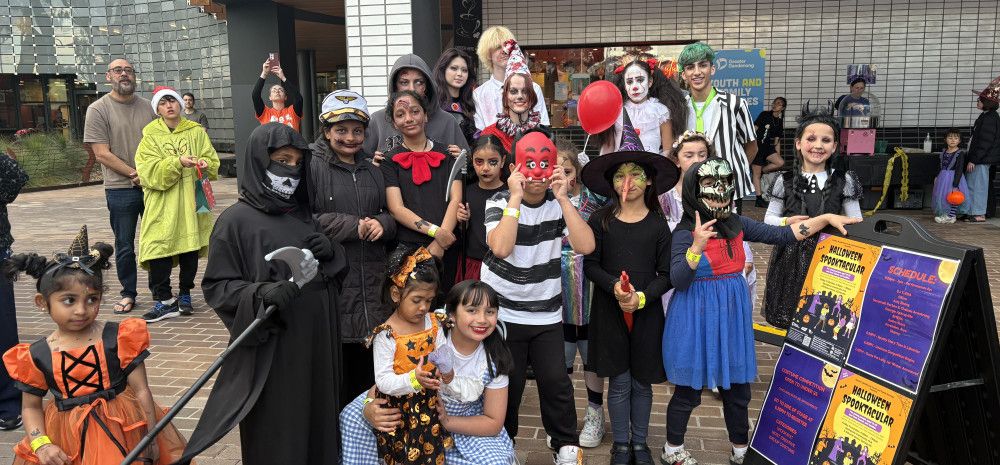 Image of a group of young people posing for a photo in Halloween costumes.